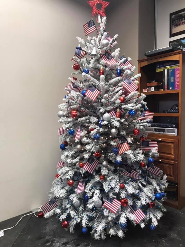 A christmas tree decorated with red , white and blue decorations and american flags.