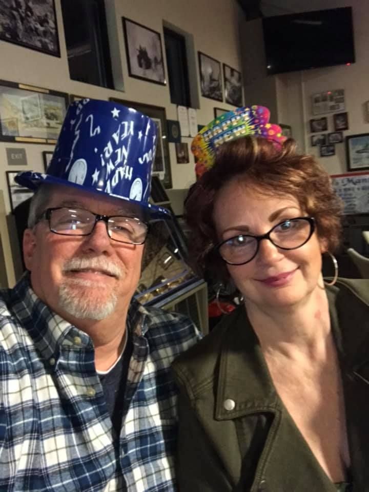 A man and a woman are posing for a picture in a room.