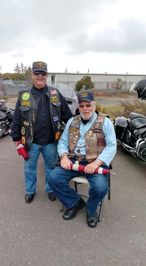 Two men are standing next to each other in front of a motorcycle.
