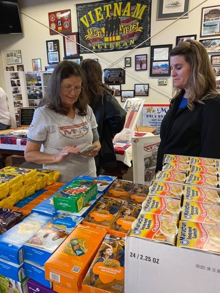 Two women are standing in front of a display of food in a store.