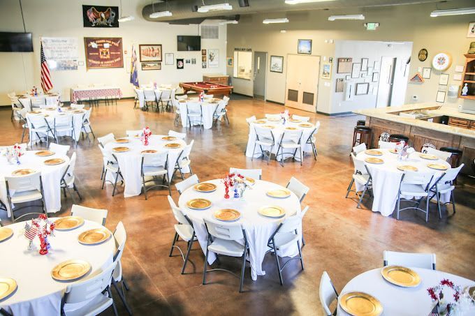 A large room filled with tables and chairs set up for a wedding reception.