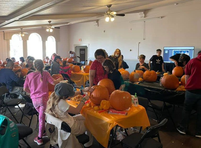 a group of people are carving pumpkins in a large room .