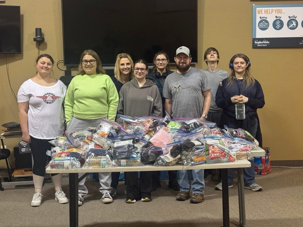 A group of people are standing around a table filled with bags of clothes.