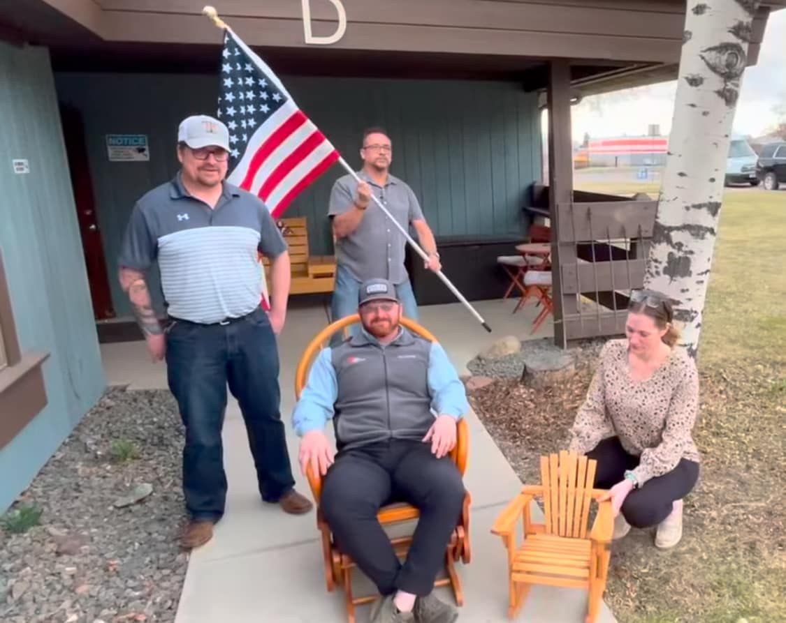 A man is sitting in a chair in front of an american flag