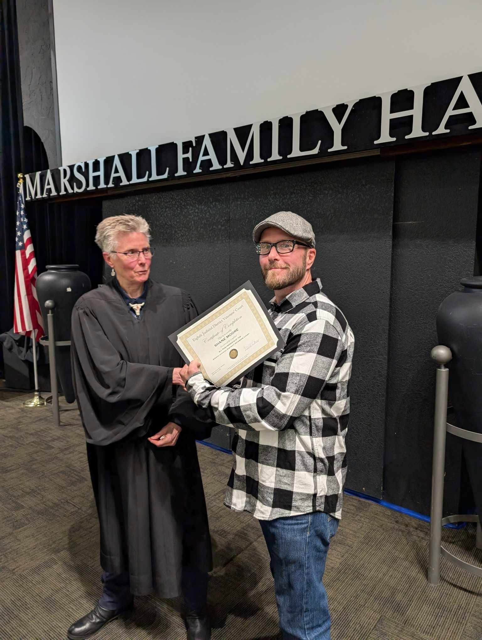 A man is standing next to a judge holding a certificate.