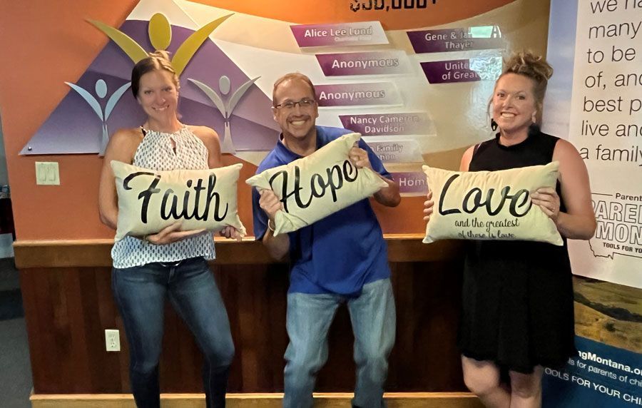 a man and two women are holding pillows that say faith hope and love