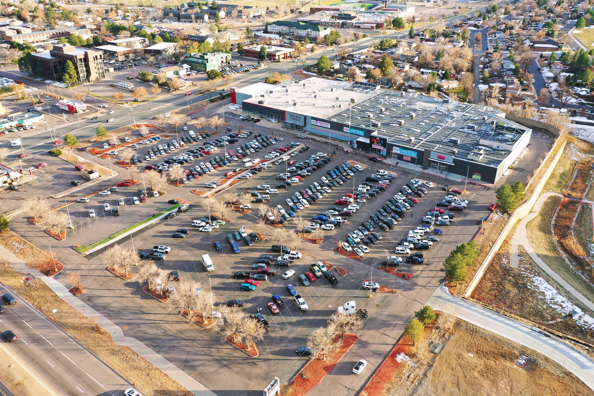 An aerial view of a parking lot with lots of cars parked in front of a large building.