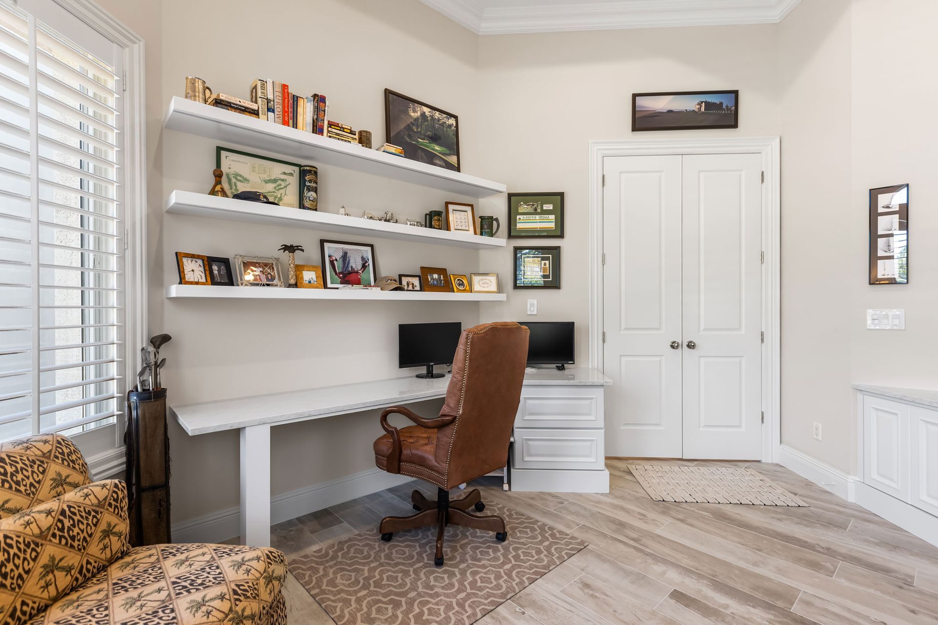A home office with a desk , chair , and shelves.