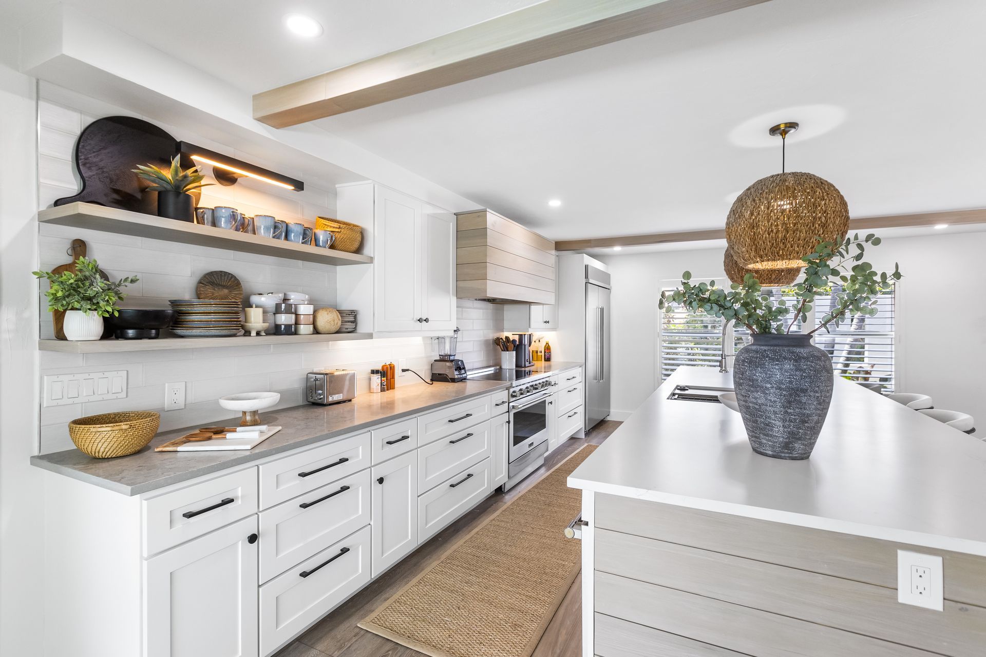 A kitchen with white cabinets , stainless steel appliances , and a large island.
