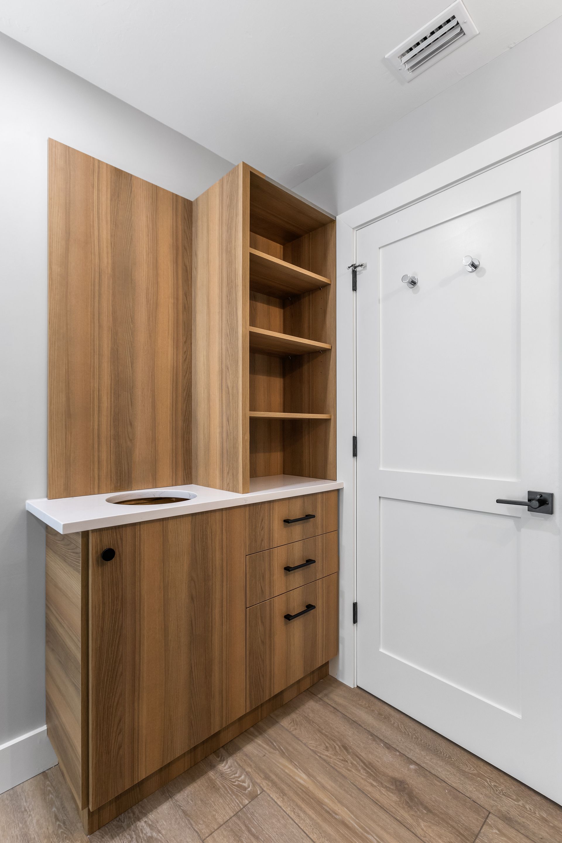 A laundry room with wooden cabinets and a sink.