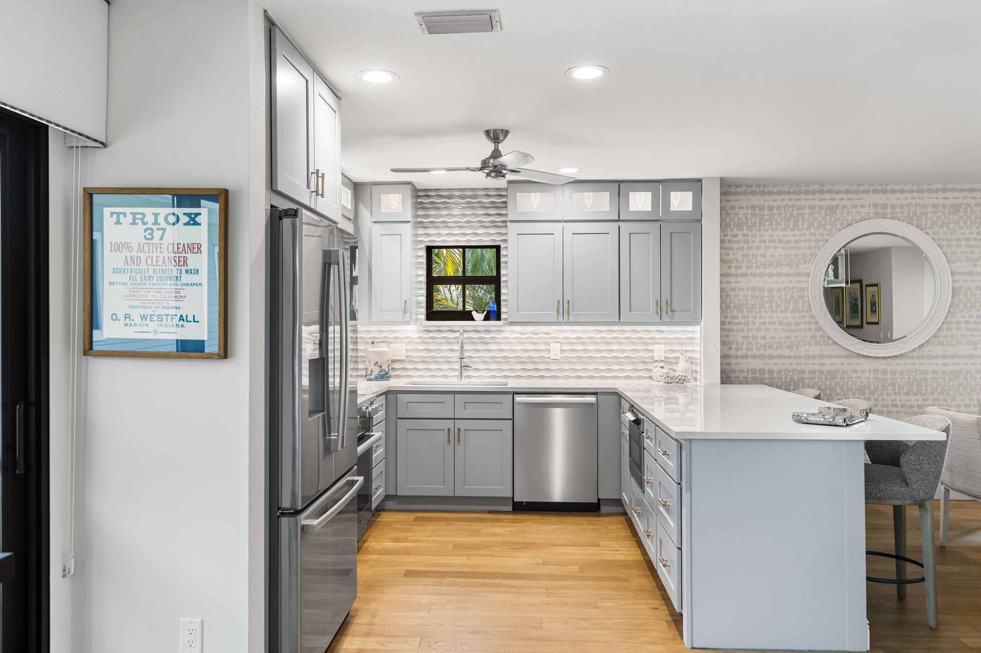 A kitchen with gray cabinets , stainless steel appliances , and a large island.