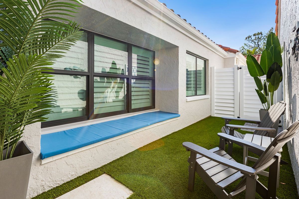 There are two chairs in the backyard of a house.