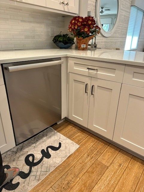 A kitchen with white cabinets and a stainless steel dishwasher.