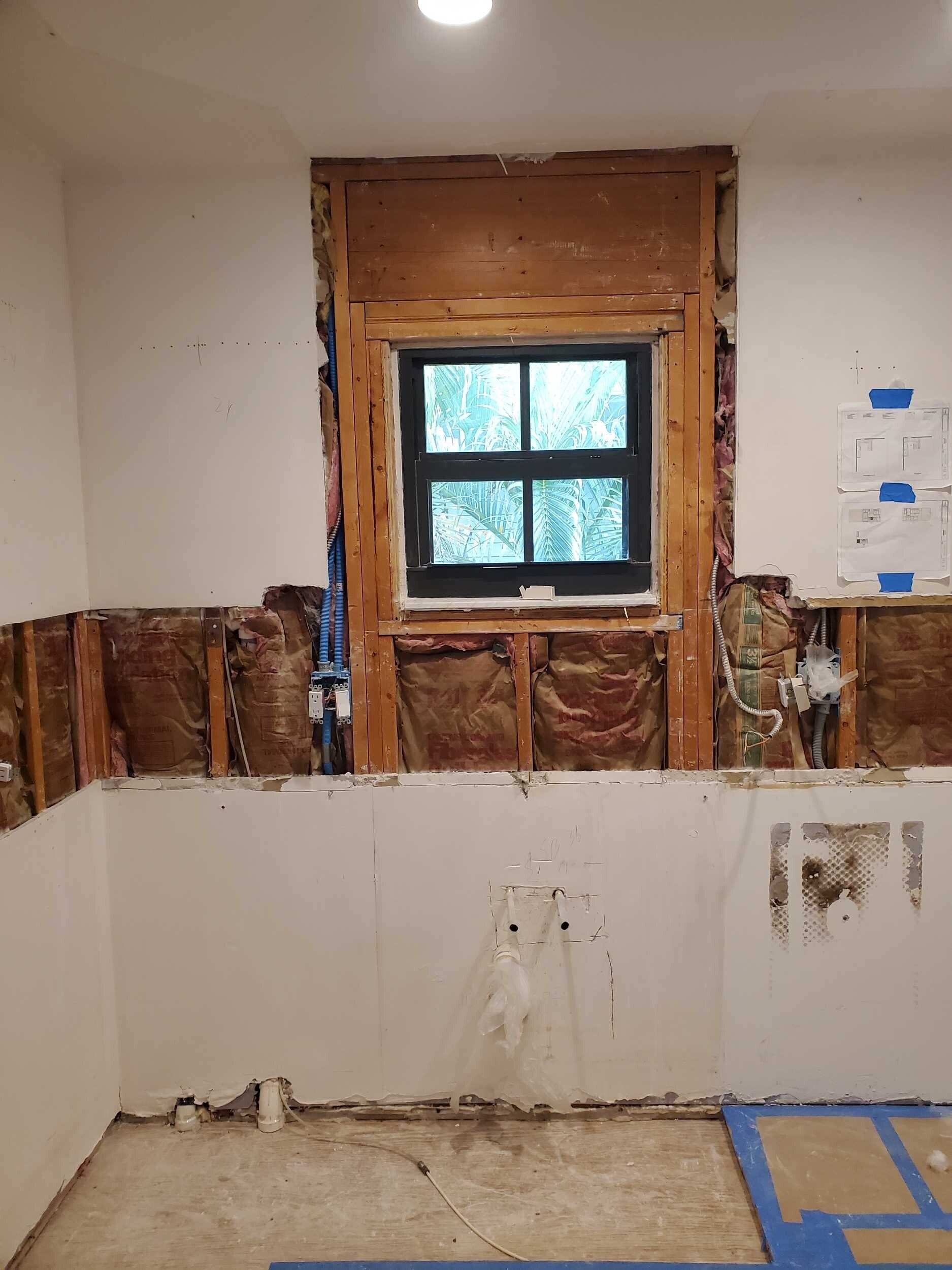 A bathroom is being remodeled with a window missing.