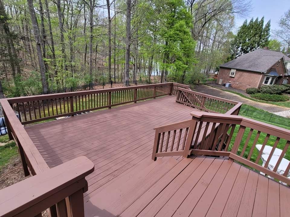 a large wooden deck with stairs leading up to it and a house in the background .