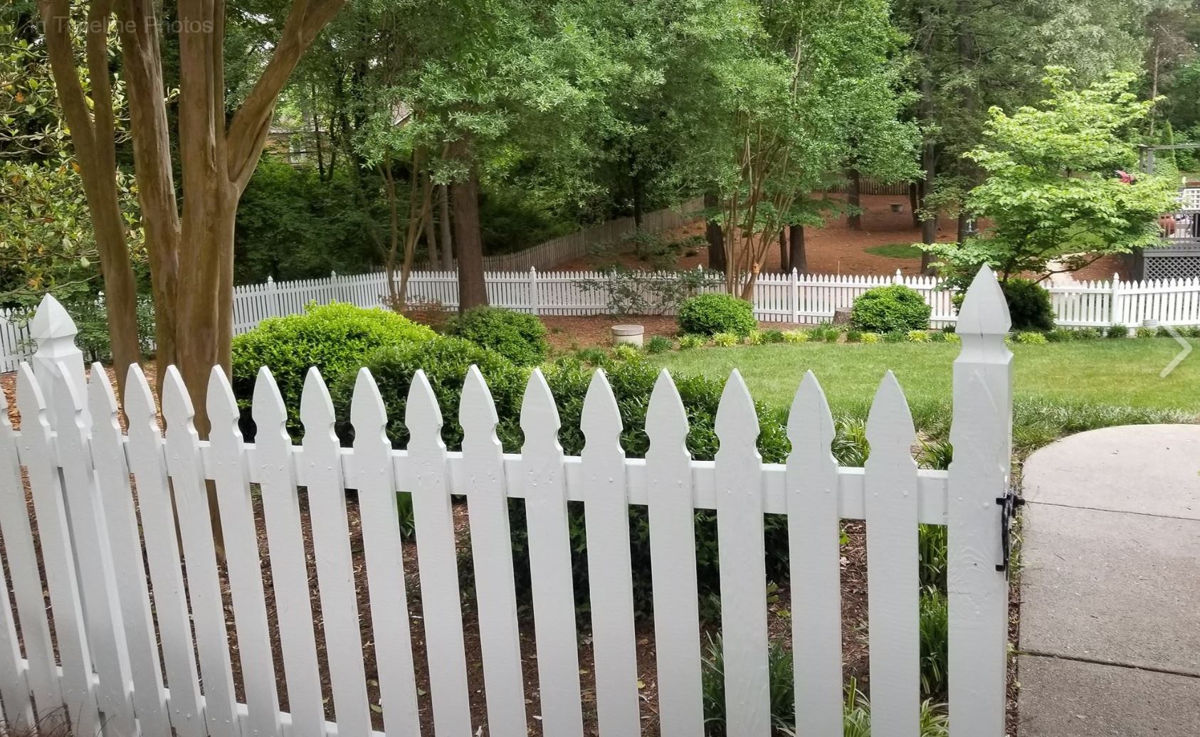 a white picket fence surrounds a lush green yard