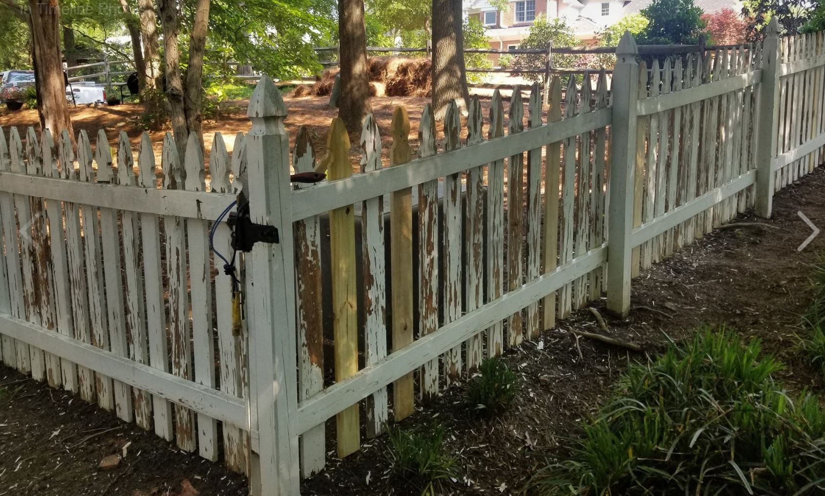 a white picket fence is surrounded by trees and grass .