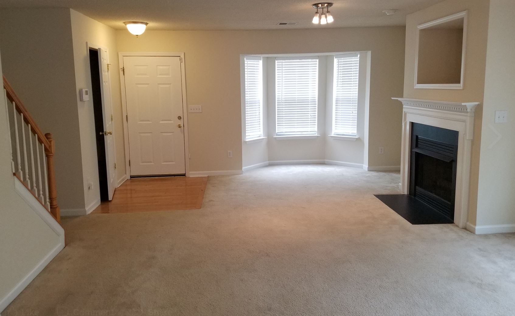 an empty living room with a fireplace and stairs