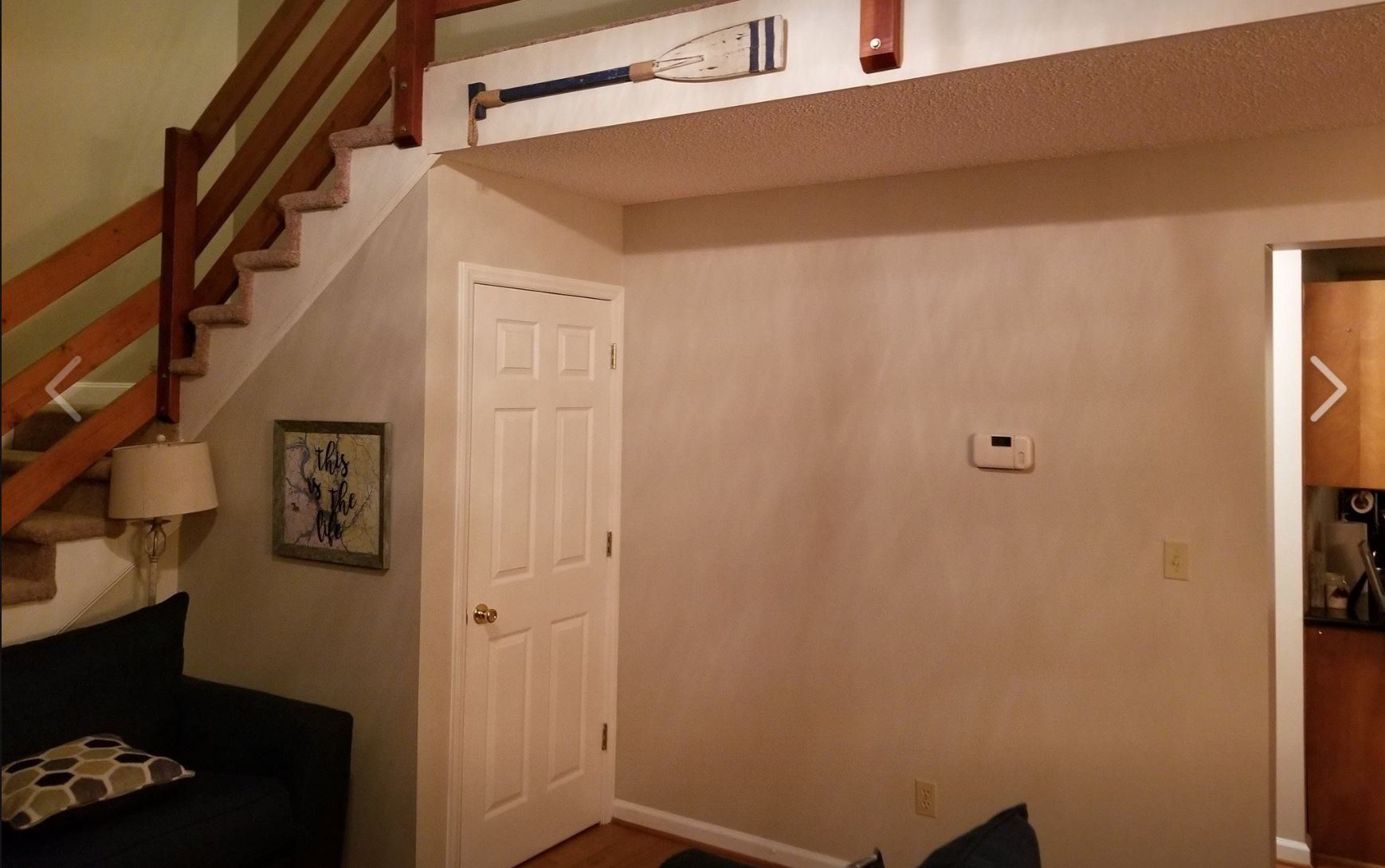 a living room with stairs and a clock on the wall