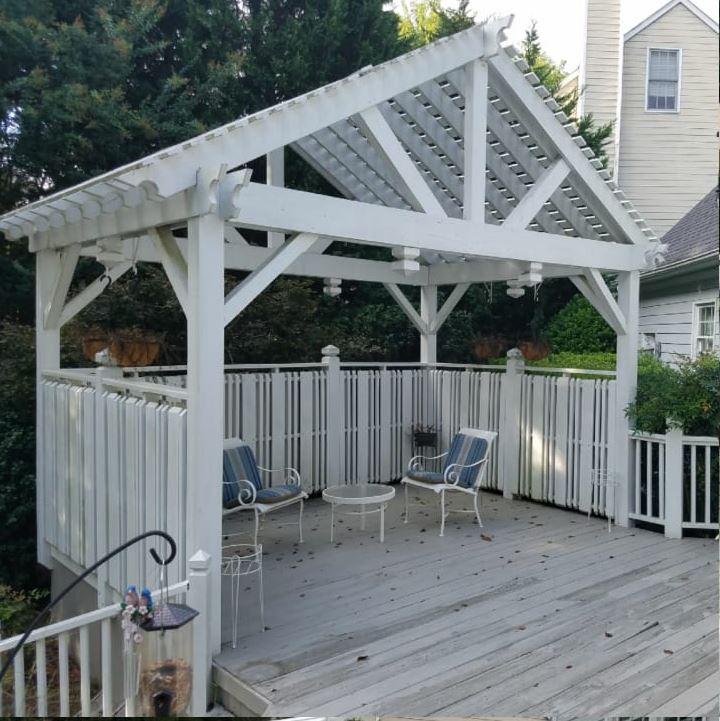 a white gazebo with chairs and a table on a deck