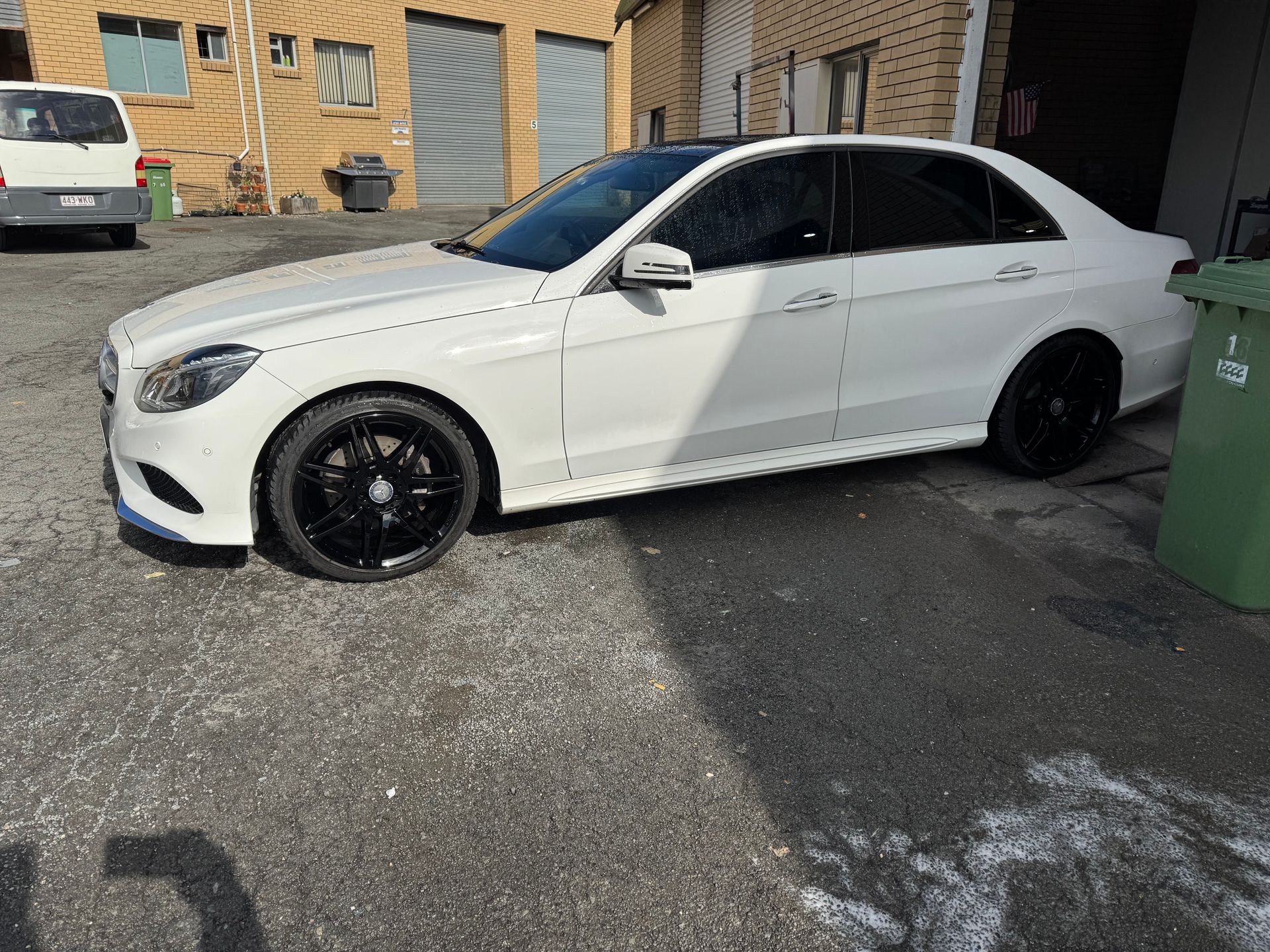 A Black Car Is Parked In A Parking Lot Next To A Trailer — Platinum Paint & Panel Southport In Southport, QLD