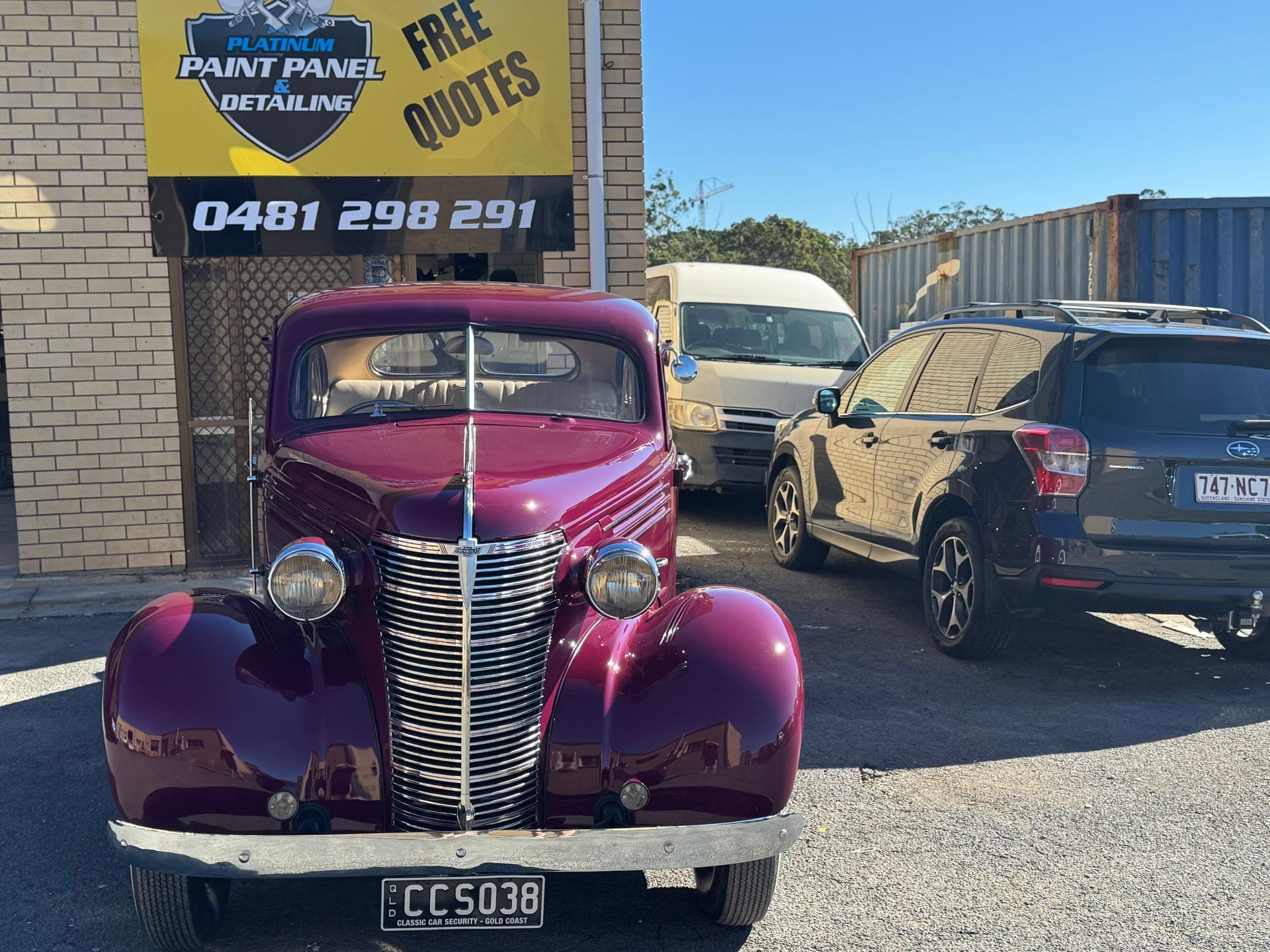 A Man Is Spray Painting A Car In A Garage — Platinum Paint & Panel Southport In Southport, QLD
