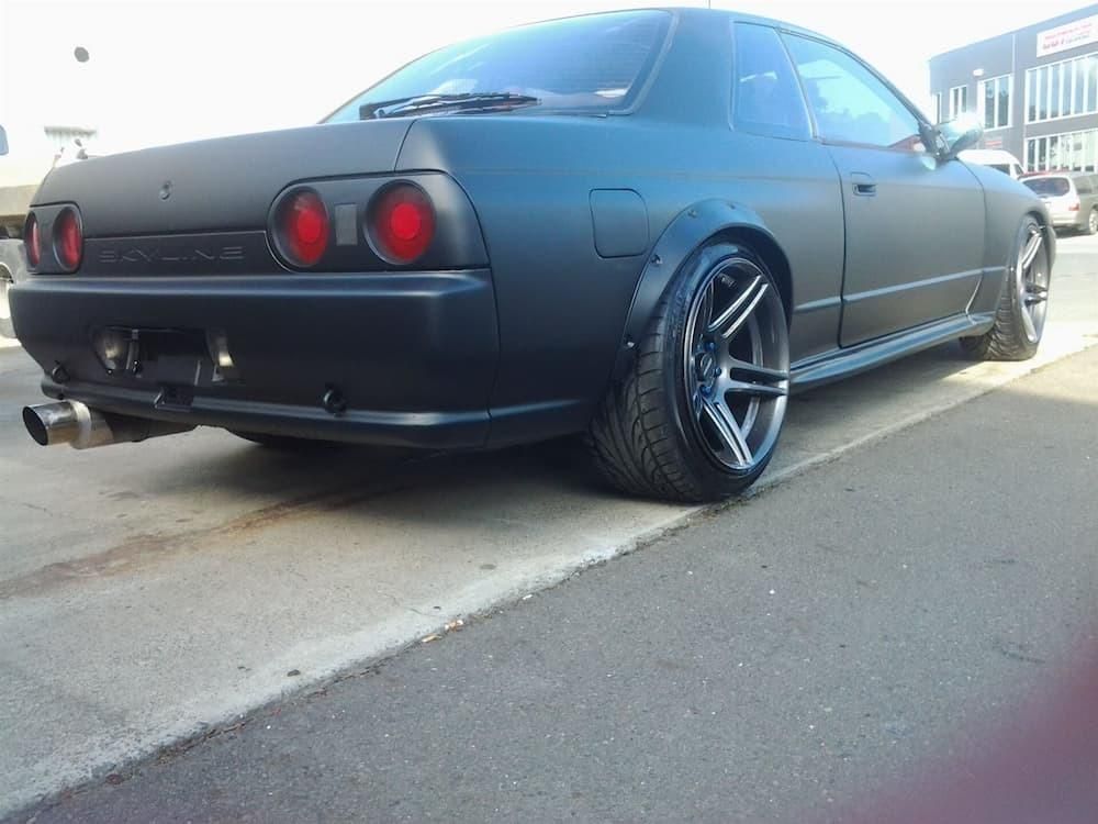 A Black Car Is Parked On The Side Of The Road — Platinum Paint & Panel Southport In Southport, QLD