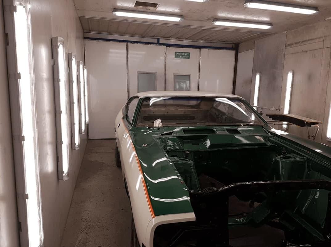 A Green And White Car Is Sitting In A Paint Booth — Platinum Paint & Panel Southport In Southport, QLD