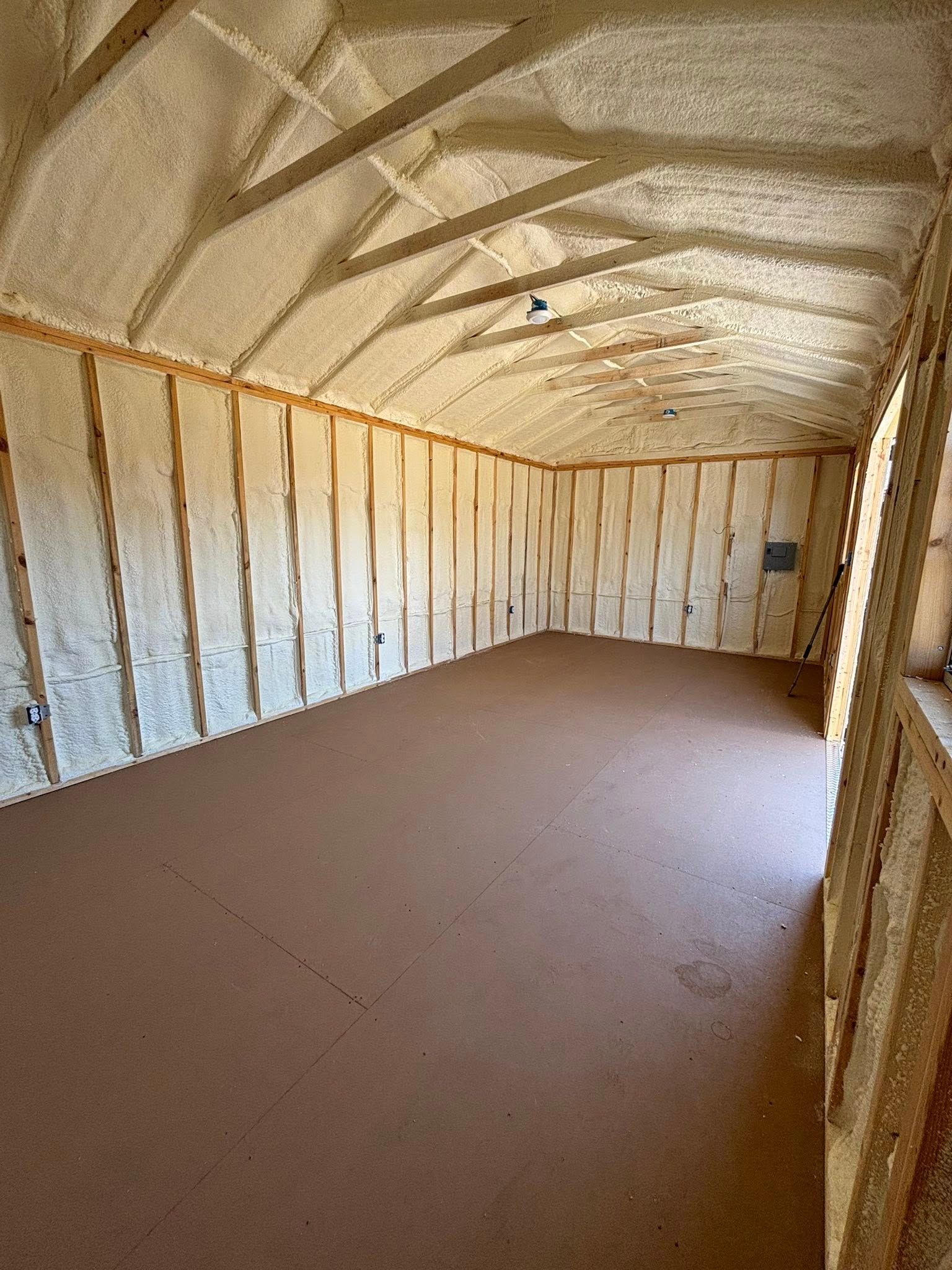 Empty insulated storage room with unfinished walls and a brown floor