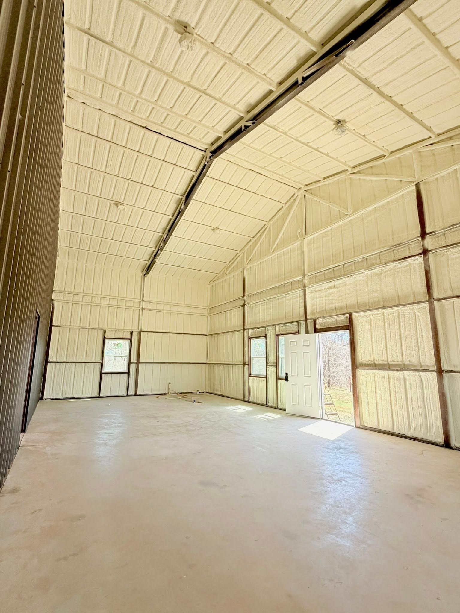 Empty industrial warehouse with beige walls, high ceiling, and bright sunlight on a concrete floor