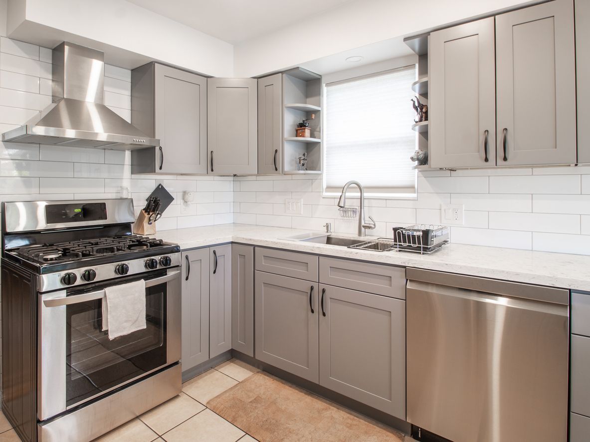 A kitchen with stainless steel appliances and gray cabinets.