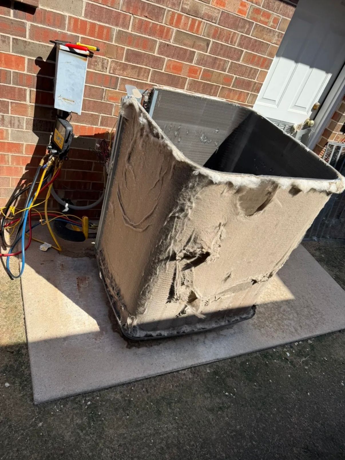 Person working on an outdoor air conditioning unit, connecting pipes.