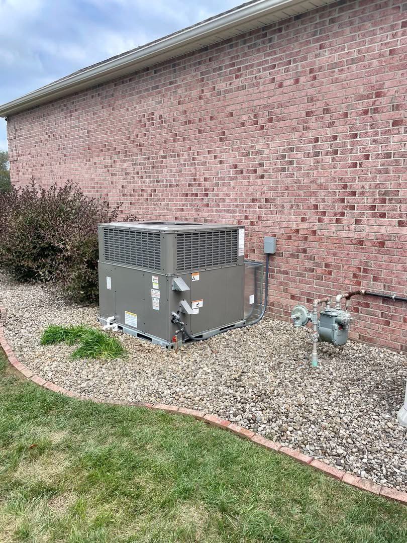Exterior wall of a house with two windows and an air conditioning unit.