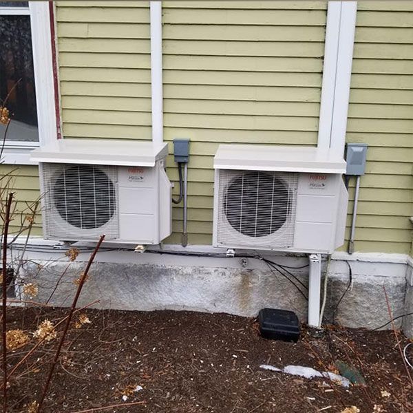 White air conditioner mounted on a wall in a room, with a window and doorway visible.