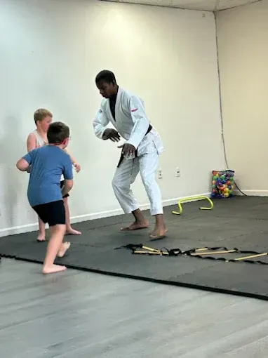 A man in a karate uniform is teaching a group of young boys.