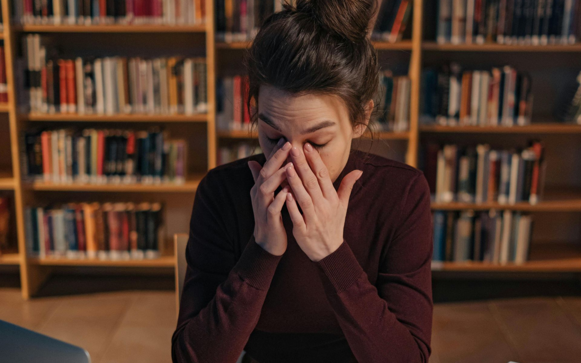 A overwhelmed Canadian therapist sitting at her desk with her face in her hands, reflecting private practice burnout, admin overload, and freeze response.