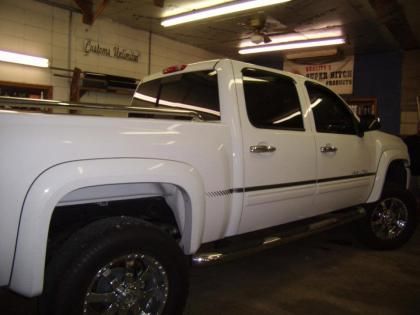 A white pickup truck with large tires and chrome accessories, parked inside a garage.