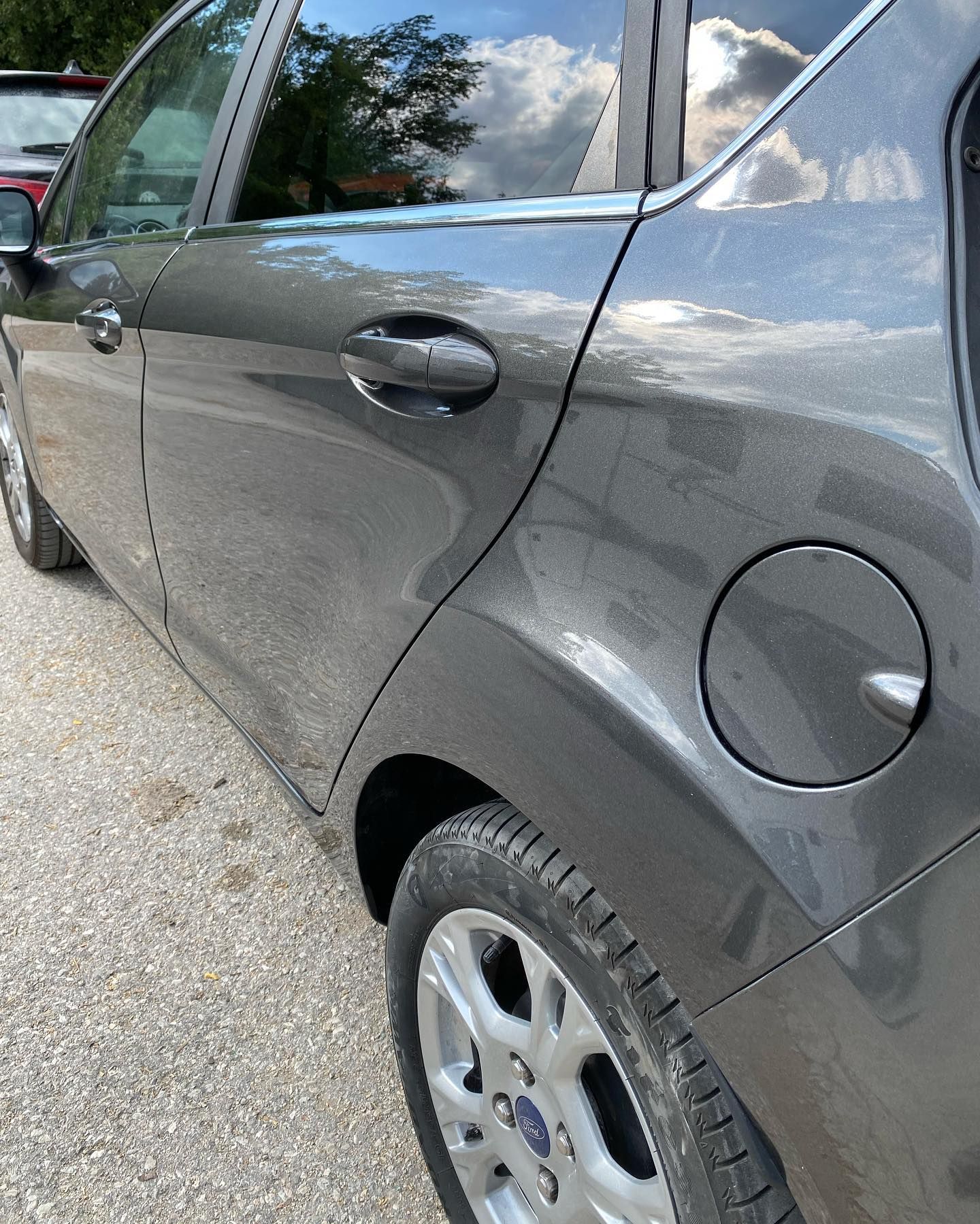 Un'auto Ford grigia parcheggiata su una superficie ghiaiosa.