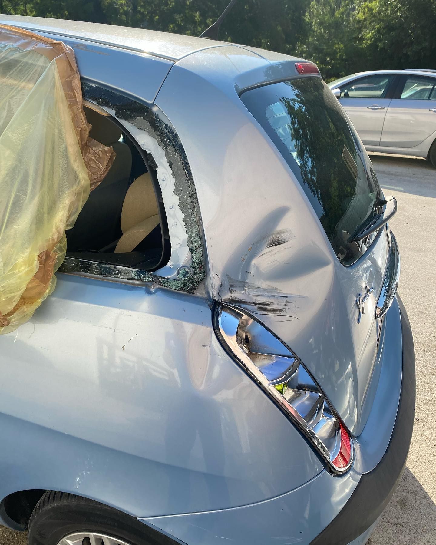 Auto azzurra danneggiata, pannello posteriore ammaccato, lunotto posteriore rotto.