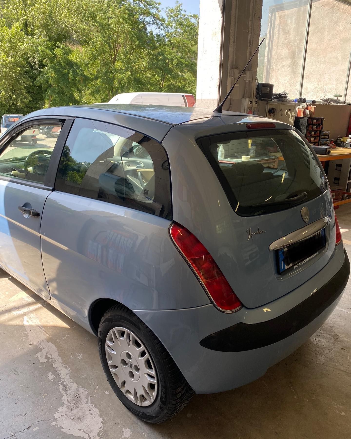 Lancia Ypsilon blu parcheggiata al chiuso, alla luce del sole.