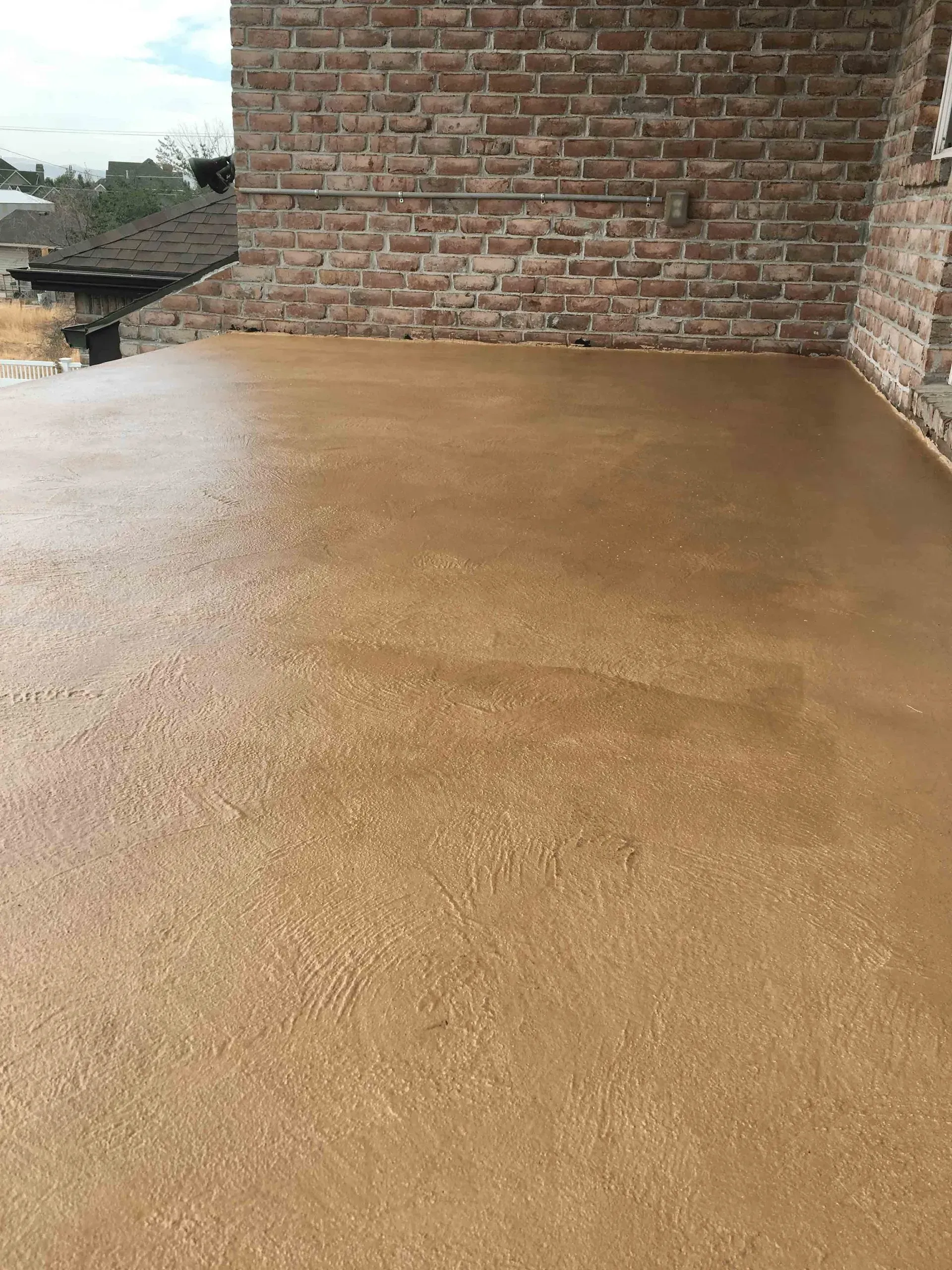 A patio with a brick wall and a concrete floor.