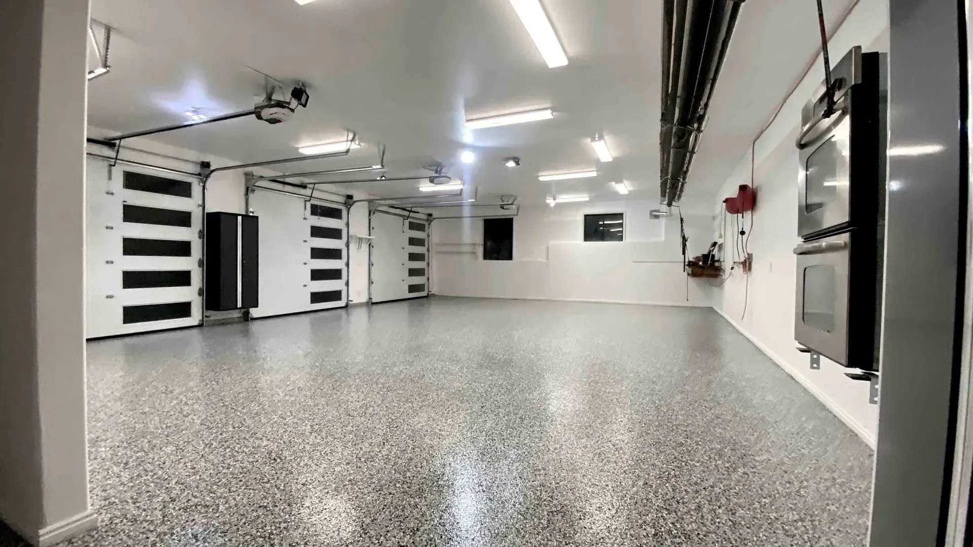 A large empty garage with a gray floor and white walls.
