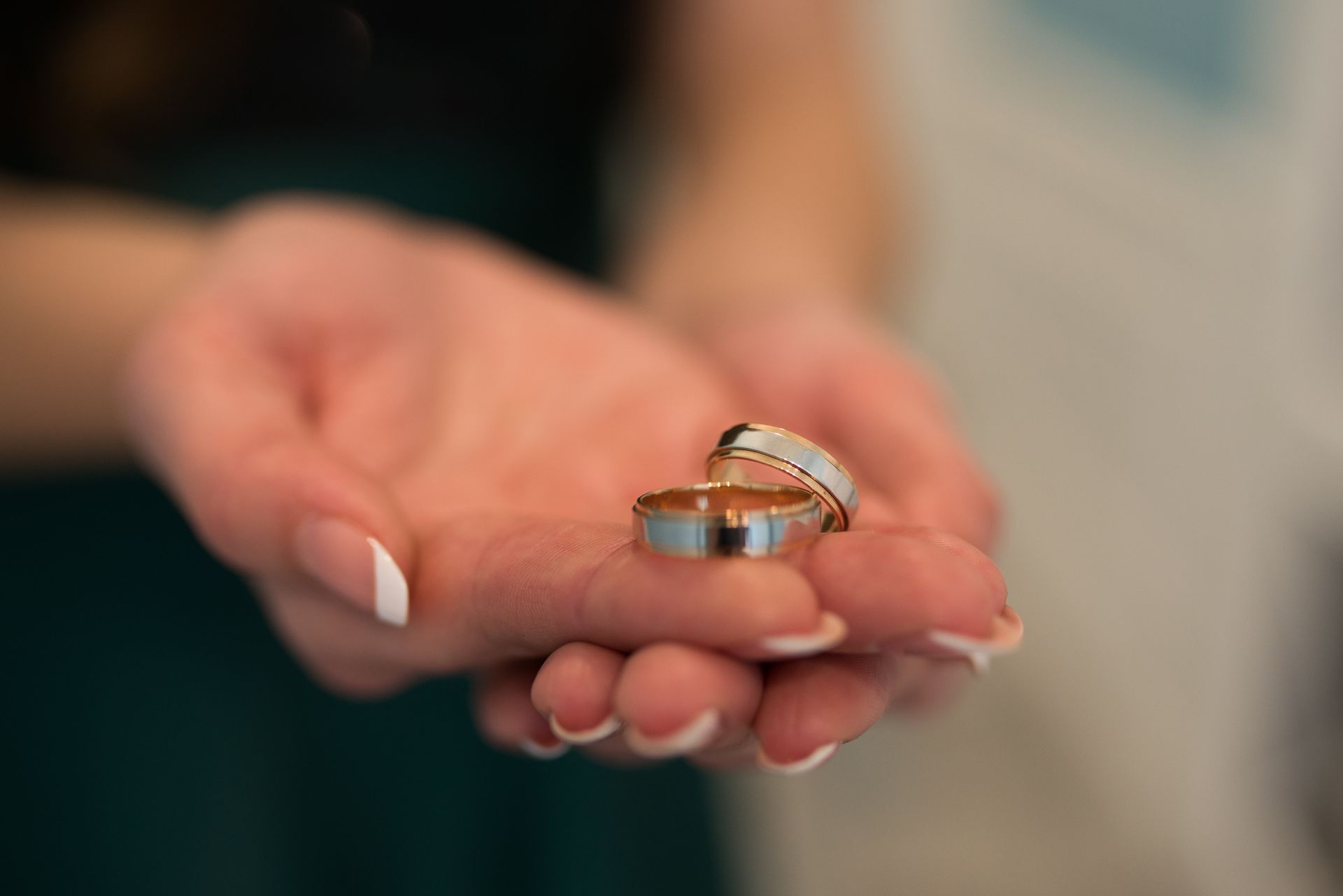 A woman is holding two wedding rings in her hands.