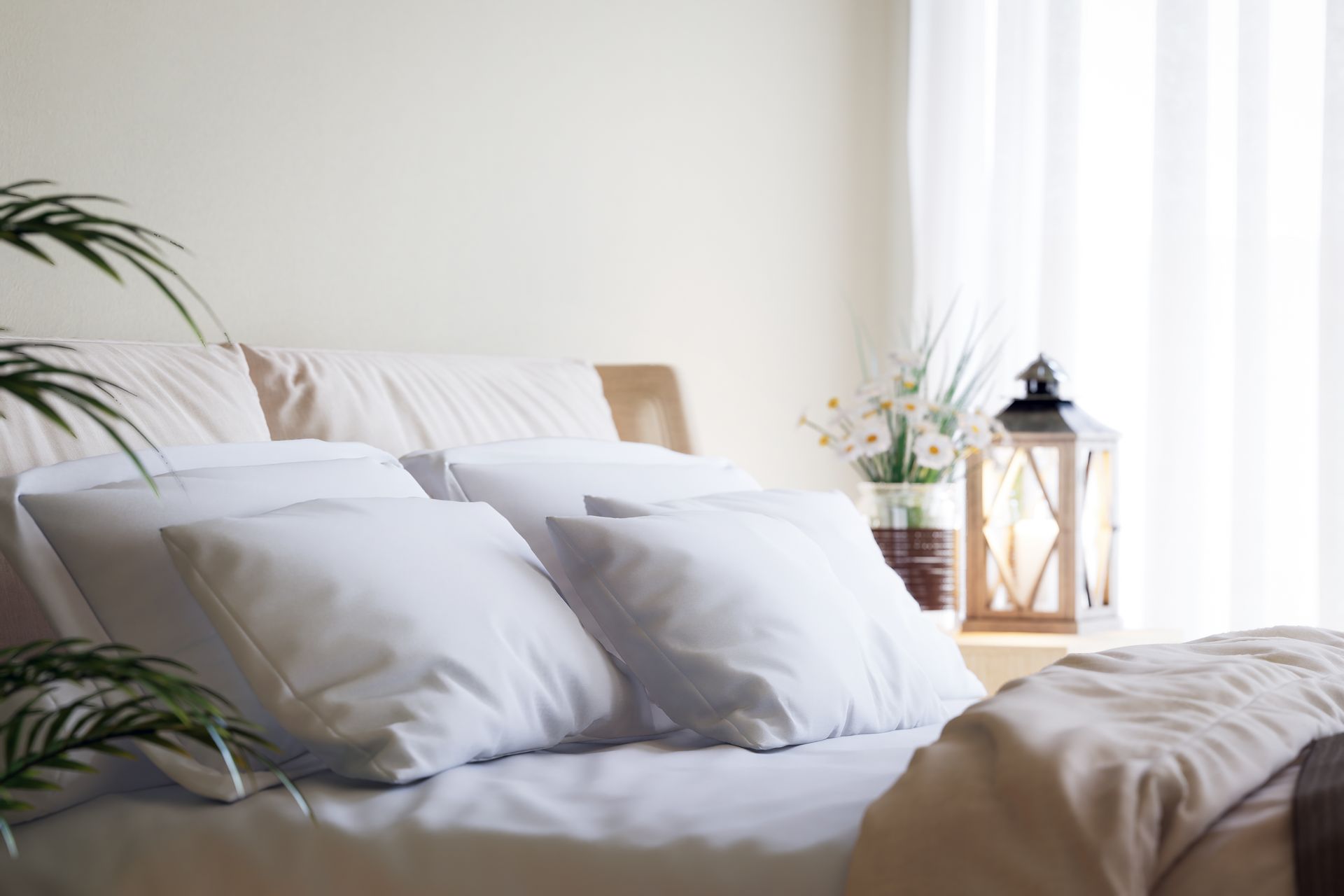 Modern white bedding on a platform bed, featuring minimalist bedroom furniture and a cozy lantern.