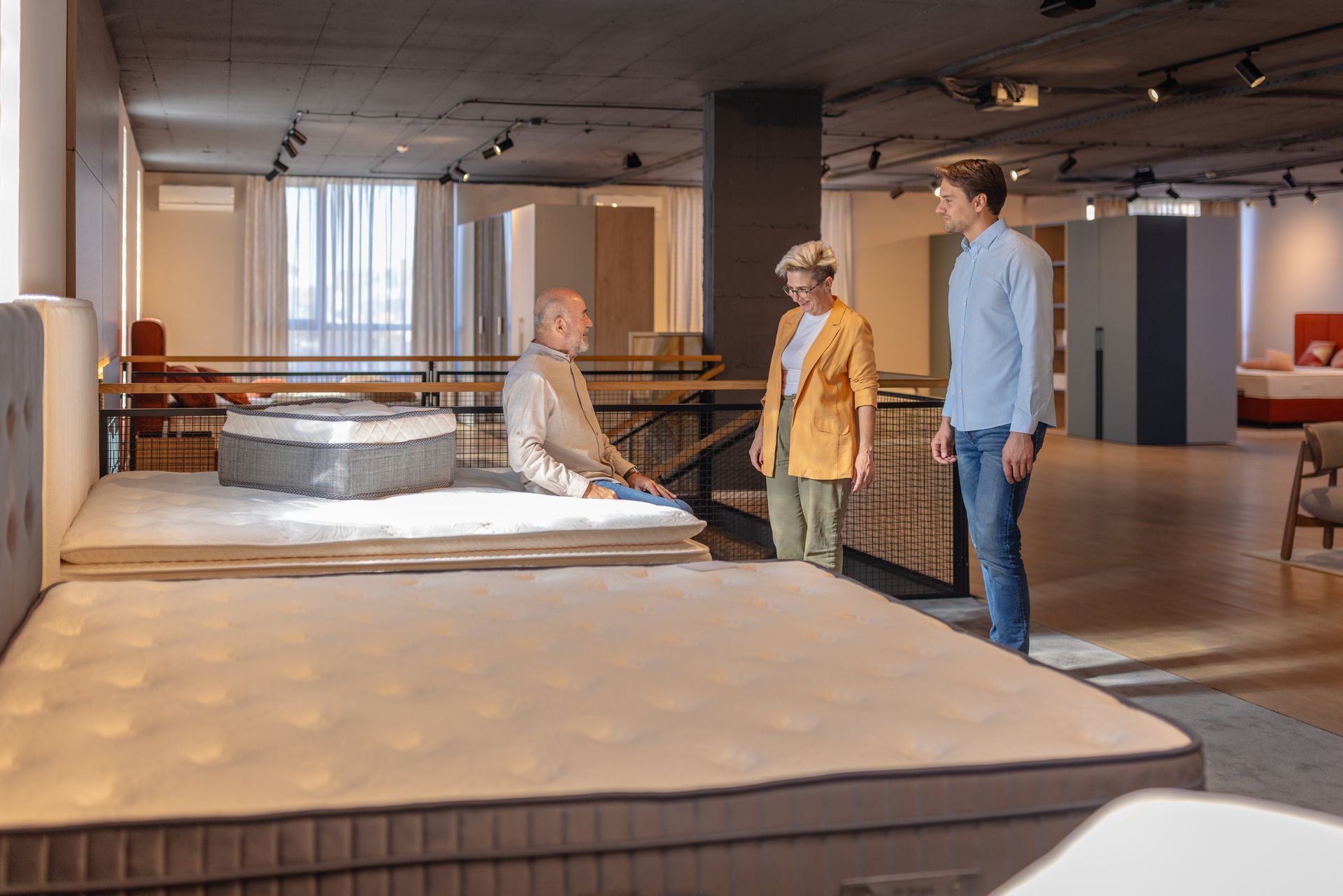 A man tests a mattress by sitting on it in a furniture store. A man tests a mattress by sitting on it in a furniture store.