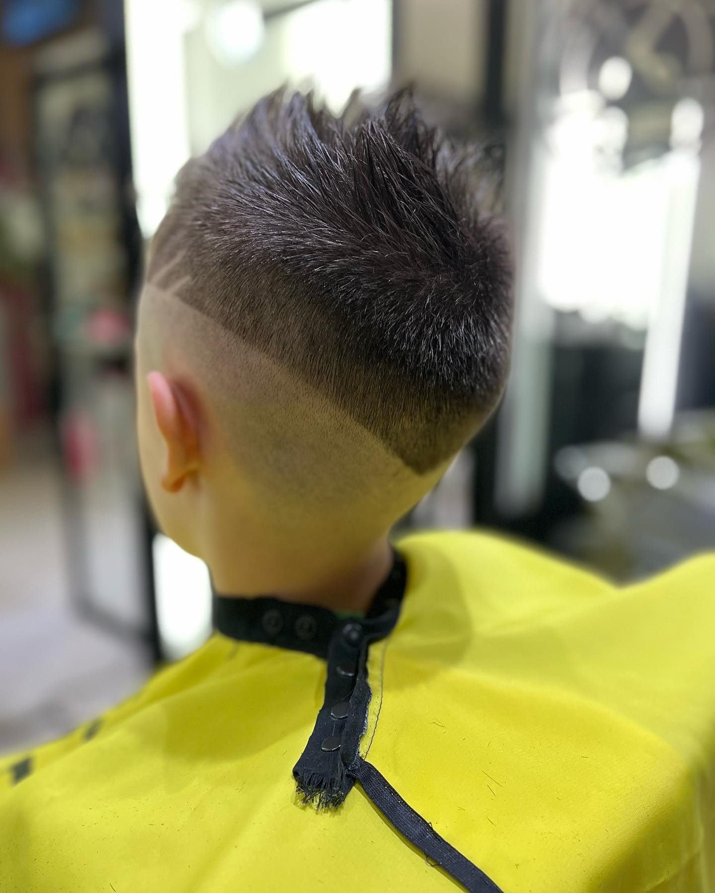 Un peinado corto y texturizado con los laterales rapados y un diseño definido y afeitado, visto desde atrás.