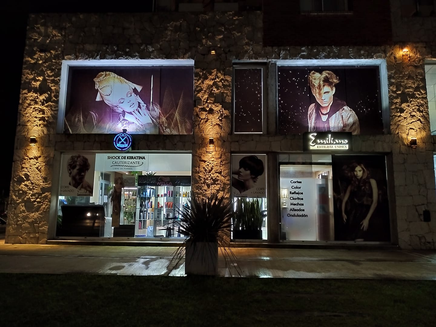 Un edificio de piedra de noche, con escaparates de dos pisos que albergan una peluquería