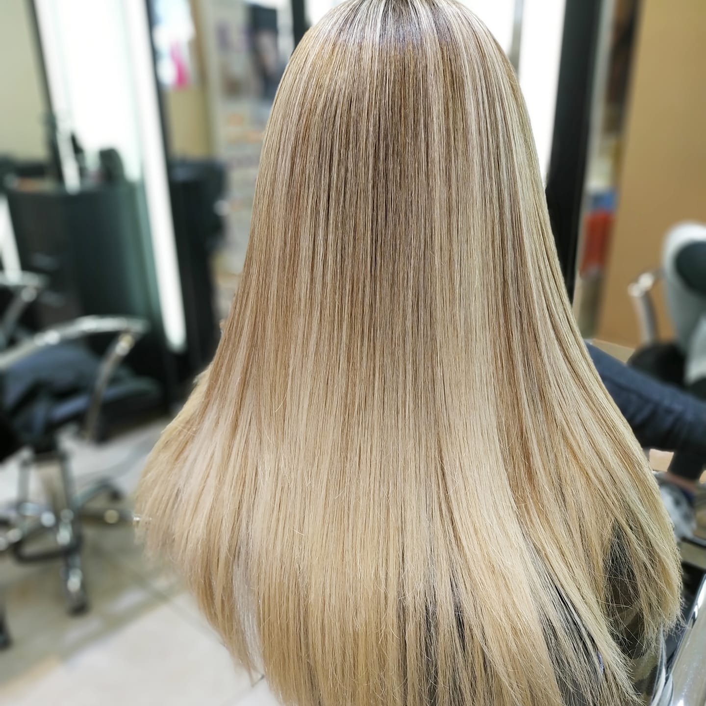 Primer plano de una melena rubia con textura ondulada, peinada larga y lisa, tomada en una peluquería.