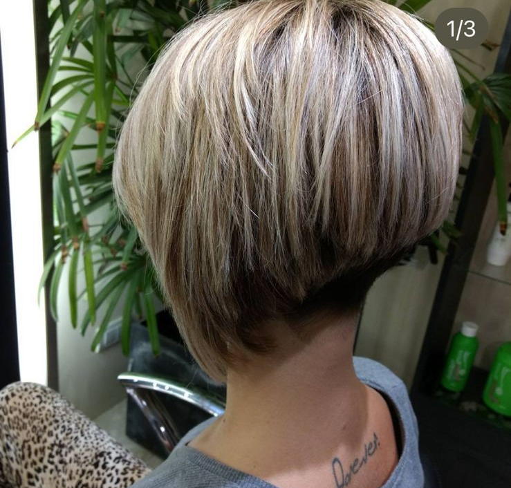 Primer plano de un corte de pelo bob capeado con mechas rubias, con la nuca más corta y desfilada, en un salón de belleza.