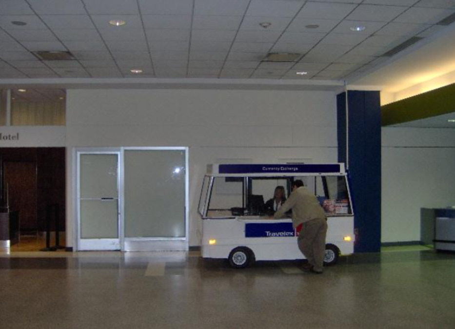 A man is standing in front of a small ice cream truck that says ' ice cream truck ' on it